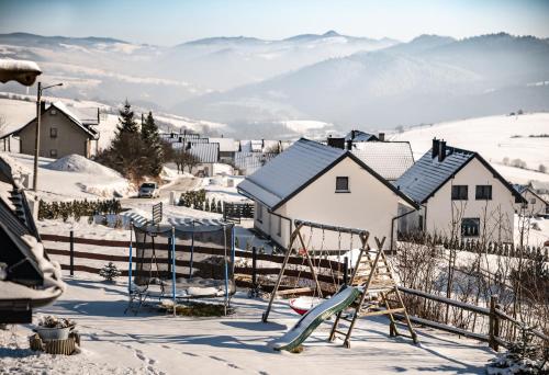a playground in the snow with mountains in the background at HRYCÓWKA Domki z Widokiem in Grywałd