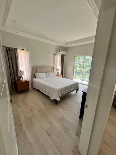 biała sypialnia z łóżkiem i oknem w obiekcie Modern condo close to Rodney Bay and Airport w mieście Gros Islet