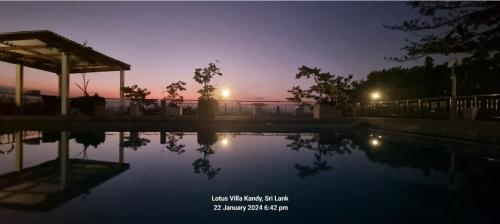 a pool of water with a sunset in the background at Lotus Villa Kandy in Peradeniya