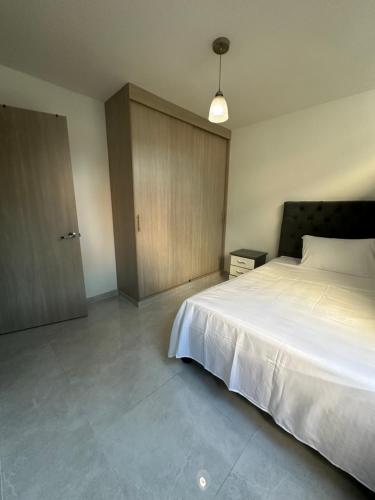 卡利的住宿－Unidad cerca a cosmocentro，卧室配有白色的床和木制橱柜。