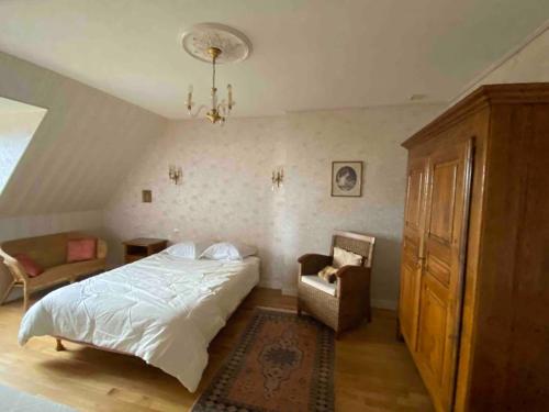 a bedroom with a bed and a chair and a chandelier at Grande maison de campagne in Lantic