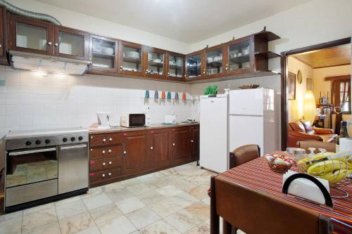 a kitchen with wooden cabinets and a white refrigerator at Suites Pinto Coelho in Caniço