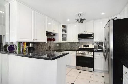 una cucina con armadietti bianchi e frigorifero nero di Collinswood room with private bathroom in shared apartment a Los Angeles