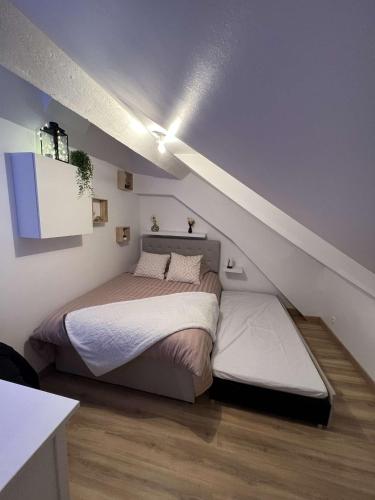 une chambre avec un lit dans un grenier dans l'établissement Le Concon Versaillais, à 5 minutes du Château de Versailles, à Le Chesnay