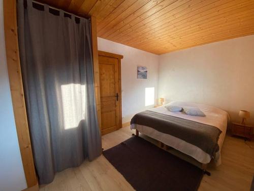une chambre avec un lit et un plafond en bois dans l'établissement Appartement à Queige, à Queige