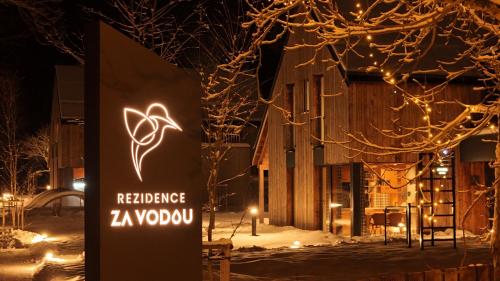 un cartello per un ristorante nella neve di notte di Rezidence Za Vodou - Ledňáček a Černý Dŭl