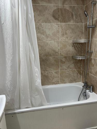 a bathroom with a bath tub with a shower curtain at Room in Essex in Pitsea