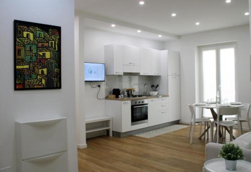 a kitchen with white cabinets and a table and a dining room at Casa D'Antò in Petralia Sottana