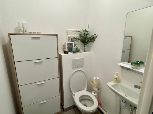 a white bathroom with a toilet and a sink at Cozy Apartment Near the Train Station in Rueil-Malmaison