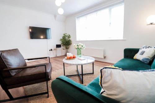 a living room with a green couch and a table at Fantastic 2 Bed 2nd Floor Flat in Reading