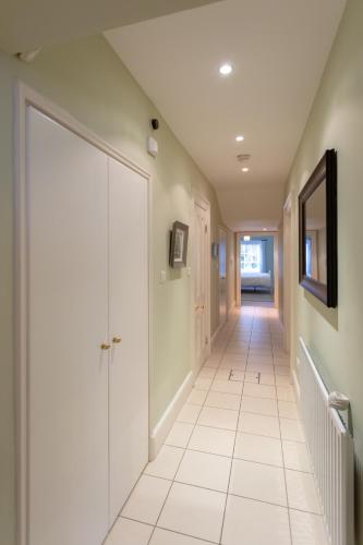 a hallway with white tile floors and a large door at Spectacular 2 Bedroom Apartment with Sunny Garden & Terrace in Dublin