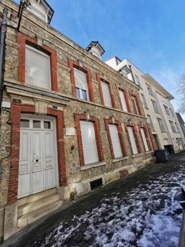 a brick building with white doors on a snowy street at Studio cosy au cœur de Reims in Reims