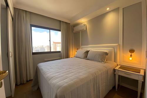 a bedroom with a large white bed with a window at Apartamento Vila Olímpia. in Sao Paulo