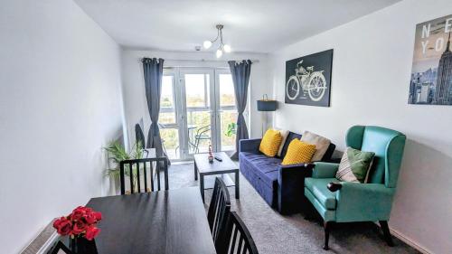 a living room with a blue couch and a table at Bright & Spacious Flat - Perfect for Exploring London , Slough & Windsor! in Slough