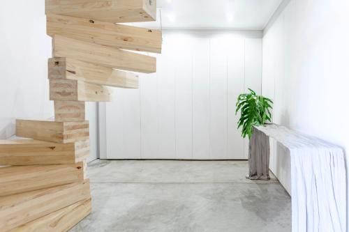 a wooden staircase in a white room with a potted plant at Calm Sandton experience in Johannesburg