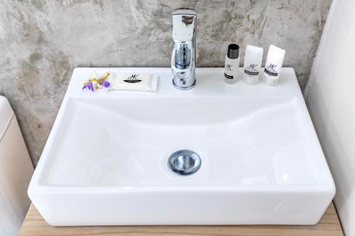 a white sink with toothbrushes and cosmetics on it at Calm Sandton experience in Johannesburg