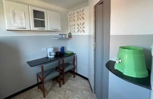 a small kitchen with a table and a green bucket at Apartamento a 1 km da Orla in Aracaju