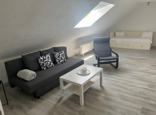 uma sala de estar com um sofá, uma cadeira e uma mesa em Moderne gemütliche 2-Zimmer Wohnung Stuttgart Bad-Cannstatt em Stuttgart