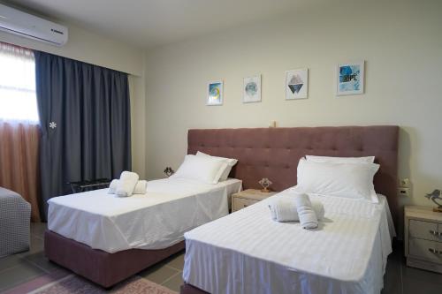 a hotel room with two beds with white sheets at Theo and MS Luxurious Apartments in Kos Town