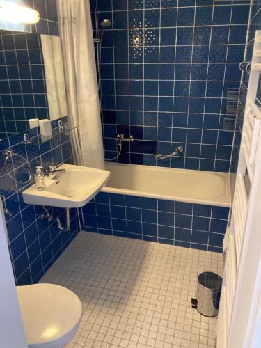 ein blau gefliestes Bad mit einem Waschbecken und einer Badewanne in der Unterkunft Apartment Henri in Schönwald