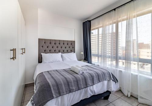 1 dormitorio con cama y ventana grande en Wavecrest 1205 Holiday Apartment, en Durban