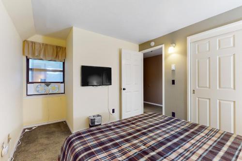 ステートラインにあるStateline Serenityのベッドルーム1室(ベッド1台、壁にテレビ付)