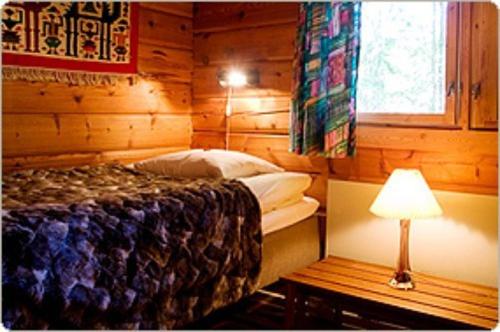 a bedroom with a bed and a table with a lamp at Tallhöjden Hotel & Cottage Lodge in Simlångsdalen