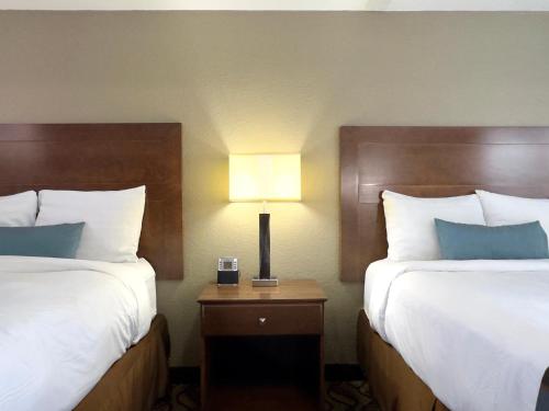 a hotel room with two beds and a table with a lamp at Super 8 by Wyndham Greensburg in Greensburg