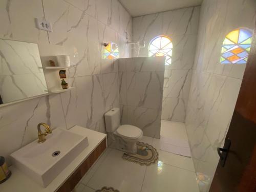 a white bathroom with a sink and a toilet at Conforto e tranquilidade no centro in Foz do Iguaçu