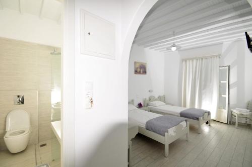 a bedroom with two beds and a bathroom with a toilet at Dimitra Pension in Mikonos
