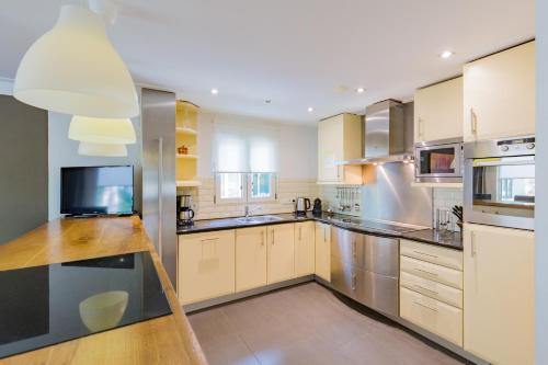 a large kitchen with white cabinets and stainless steel appliances at 8 pers vakantiehuis met natuur- sauna en bubbelbad in Diessen