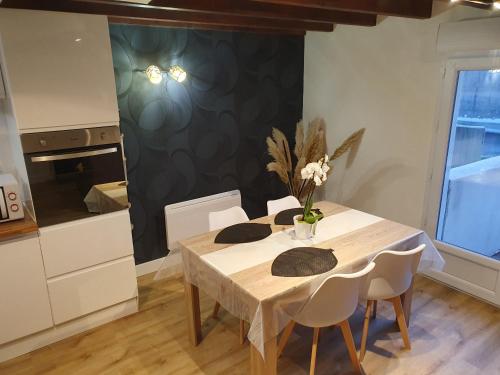 une cuisine avec une table et des chaises blanches ainsi qu'une cuisine avec une cuisinière dans l'établissement Appartement cosy et relooké, à Saujon