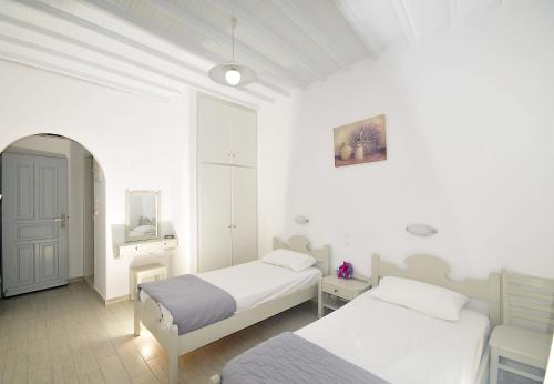 ein weißes Zimmer mit 2 Betten und einem Spiegel in der Unterkunft Dimitra Pension in Mykonos Stadt