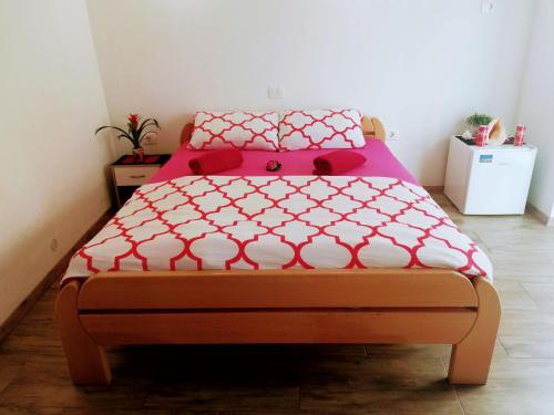 Bett mit einer roten und weißen Bettdecke in einem Zimmer in der Unterkunft Apartma SunySun in Koper