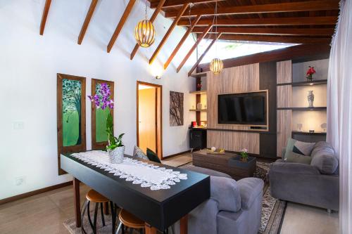 a living room with a table and a tv at Pousada Cavaleiro dos Pireneus in Pirenópolis