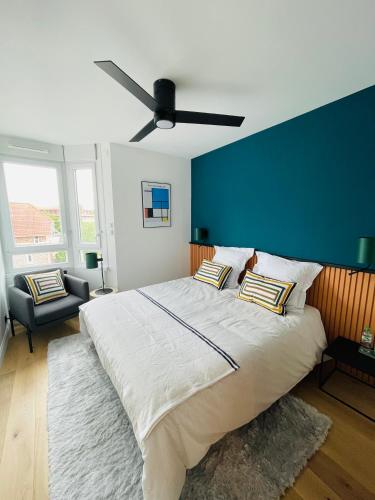 une chambre avec un grand lit avec un mur bleu dans l'établissement Au cœur du Croisé Laroche, à Marcq-en-Barœul