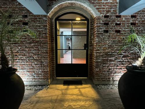 uma porta preta numa parede de tijolos com plantas em Nuevo Hotel Ciervo de Oro- By HVH em Villa Carlos Paz