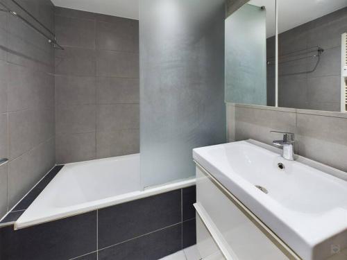 a bathroom with a sink and a tub and a mirror at Studio - central, calme et bien placé in Brussels