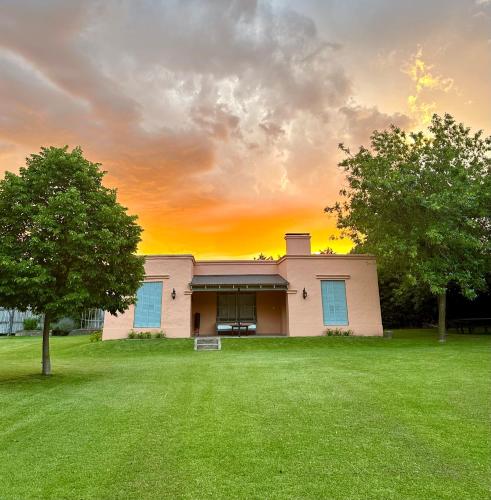 een huis met een groen gazon voor de zonsondergang bij Los Narcisos in San Antonio de Areco