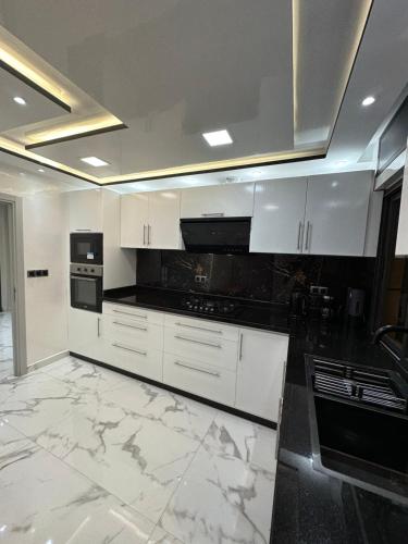 uma cozinha com armários brancos e electrodomésticos pretos em Welcome to THE VIEW! em Al Hoceïma