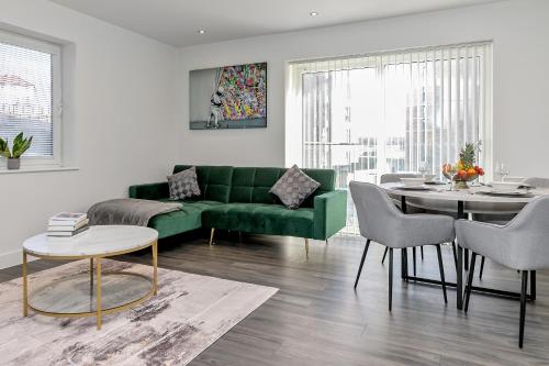 a living room with a green couch and a table at PREMIUM AIRPORT SUITE~Free Parking~LUXURY Condition~BALCONY~FANTASTIC Location Close To Train Station & Town Centre in Luton