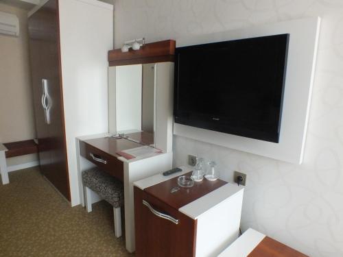 Zimmer mit einem TV und einer Kommode mit einem Spiegel in der Unterkunft Grand Ahos Hotel in Ereğli