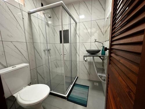 a bathroom with a toilet and a glass shower at Village Hostel in Petrópolis