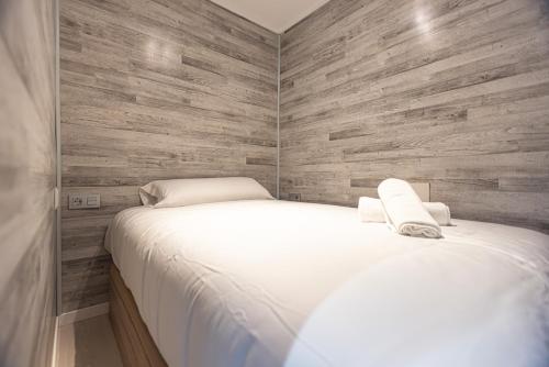 een slaapkamer met een wit bed en een houten muur bij Apartamento Atlas in Sierra Nevada