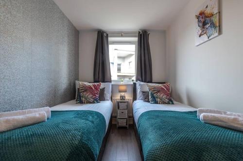 two twin beds in a room with a window at Apartment in Ashford 2 Bedroom private parking for contractors, families & holiday in Kennington