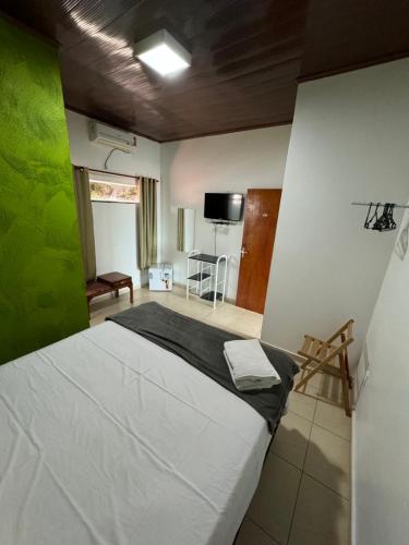 a bedroom with a white bed with a green wall at Pousada Caminho das Cachoeiras Pirenopolis in Pirenópolis