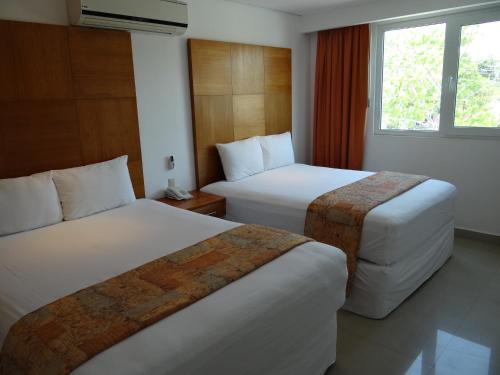 una camera d'albergo con due letti e una finestra di Hotel Suites Gaby a Cancún