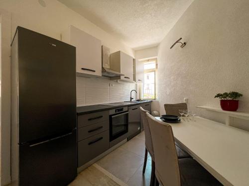 uma cozinha com um frigorífico preto e uma mesa com cadeiras em Apartment Vladimir em Kaštela