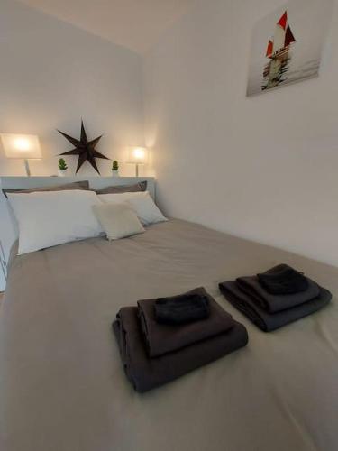une chambre blanche avec un lit avec deux serviettes dessus dans l'établissement Roscoff  - Studio cosy 3*, à Roscoff