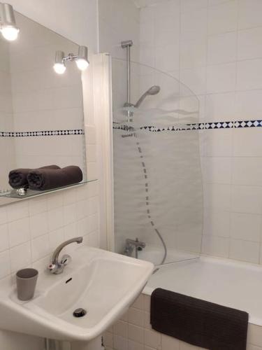 une salle de bain blanche avec une douche et un lavabo dans l'établissement Roscoff  - Studio cosy 3*, à Roscoff